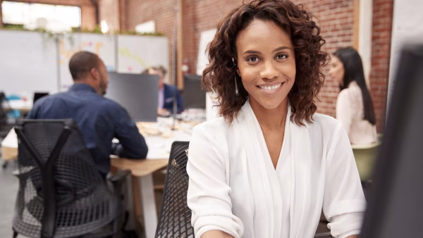 Portrait Of Female Customer Services Agent Working At Desk In Call Center